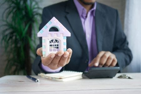 man with calculator holding house symbol